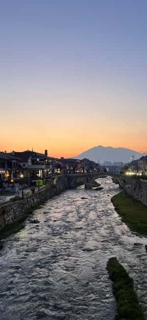 The Lumbardhi river through Prizren at dusk, minaret and Sharr ridge behind